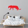 מדבקת פומה אדומה מודבקת על קיר מעל מיטה זוגית